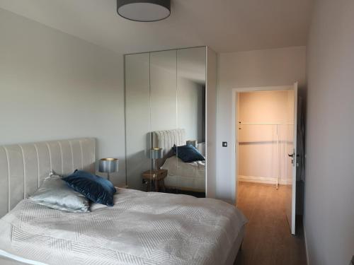 グダニスクにあるApartament Neptunのベッドルーム(青い枕と鏡付きのベッド1台付)