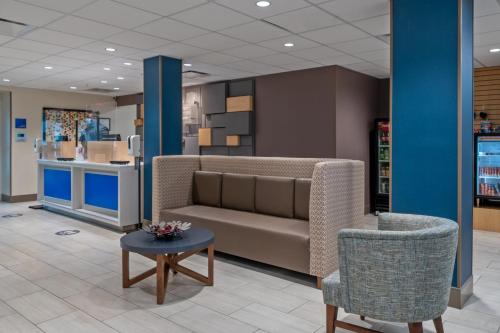 a waiting room with a couch and a table and chairs at Holiday Inn Express Hotel & Suites Woodbridge by IHG in Woodbridge