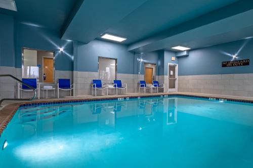 a swimming pool with blue chairs in a building at Holiday Inn Express Hotel & Suites Woodbridge by IHG in Woodbridge