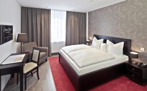 Pokój hotelowy z łóżkiem, biurkiem i biurkiem w obiekcie Limes Hotel w mieście Wehrheim