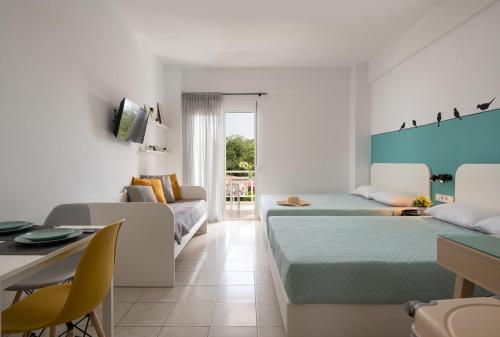 a hotel room with two beds and a couch at Kochyli Beach Studios in Nea Plagia