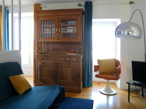 a living room with a large wooden cabinet and a chair at Bel appartement avec vue directe sur loire in Saint-Paimboeuf