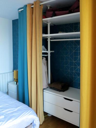 - une chambre avec un lit et un placard aux murs bleus dans l'établissement Bel appartement avec vue directe sur loire, à Saint-Paimboeuf