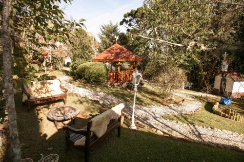 a garden with a gazebo and a bench and a table at Pousada das Hortênsias in Campos do Jordão
