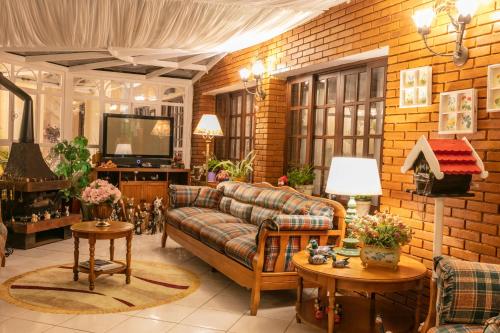 a living room with a couch and a tv at Pousada das Hortênsias in Campos do Jordão