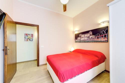 a bedroom with a red bed and a painting on the wall at Apartment Colosseo in Rome