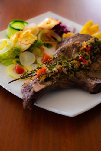a plate of food with meat and vegetables on a table at Hotel la Giralda in Ibarra