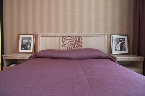a bedroom with a purple bed with two pictures at Апартаменты на Спортивной in Tolyatti