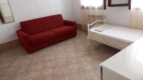 ein rotes Sofa in einem Zimmer mit einem Bett in der Unterkunft CANAL VIEW in Venedig