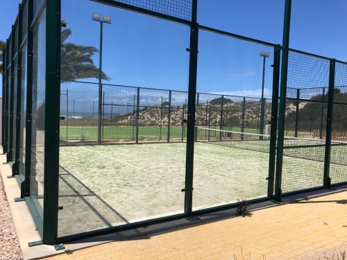 a tennis court is seen through a window at São Torpes by Campigir in Sines