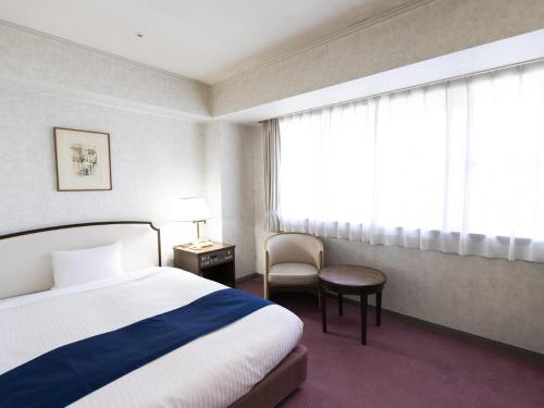神戸市にあるアリストンホテル神戸のベッド1台、椅子、窓が備わる客室です。