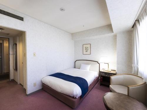 a bedroom with a bed and a desk and a chair at Ariston Hotel Kobe in Kobe