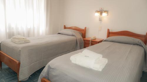 two beds in a room with white towels on them at HOTEL 3 DE ABRIL in Mar del Plata