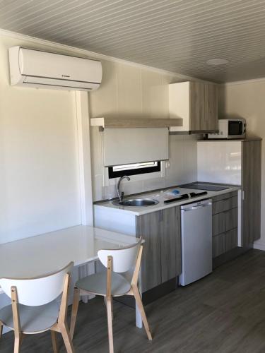 a kitchen with a table and two chairs and a sink at São Torpes by Campigir in Sines