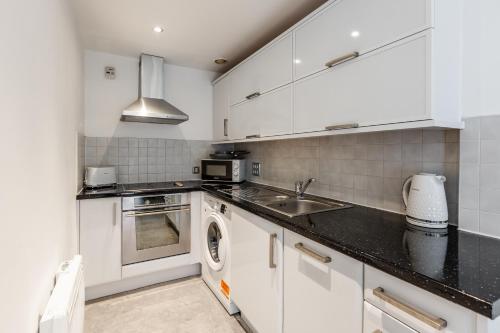 a white kitchen with a sink and a dishwasher at RST Cumberland Street in Liverpool