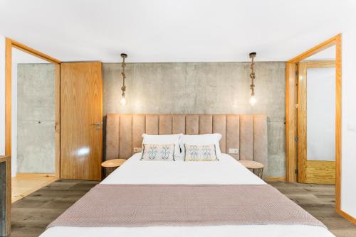 a bedroom with a large white bed with two pillows at Gerês Villas in Geres