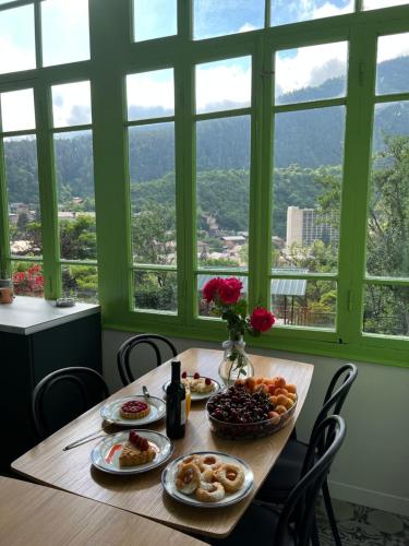 a table with plates of food on it with windows at Polifonia Inn Borjomi in Borjomi