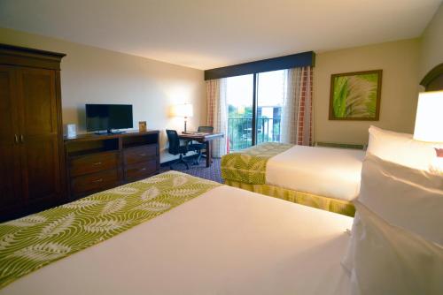 a hotel room with two beds and a television at Rosen Inn Closest to Universal in Orlando