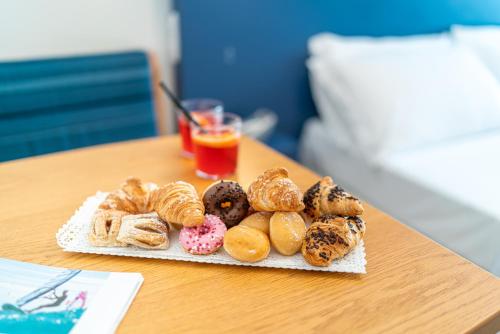 een tafel met een schaal donuts en een glas sinaasappelsap bij Hotel Alexander in Bibione