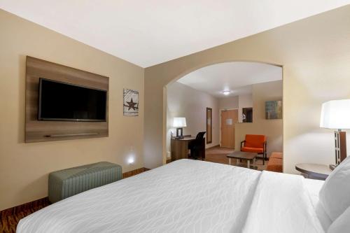 a hotel room with a bed and a flat screen tv at Best Western Plus DFW Airport Suites in Irving