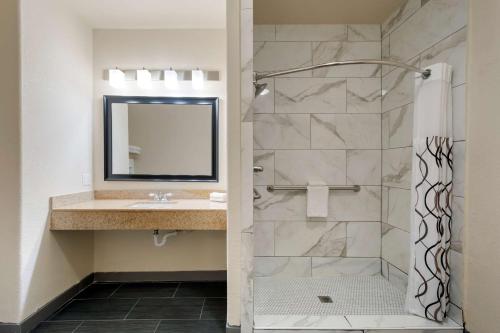 a bathroom with a shower with a sink and a mirror at Best Western Plus DFW Airport Suites in Irving