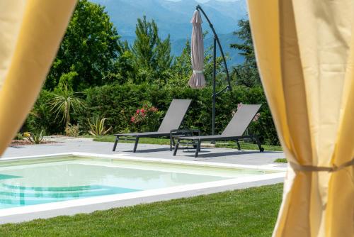 a pool with two chairs and a umbrella at Villa San Martino in Albiano dʼIvrea