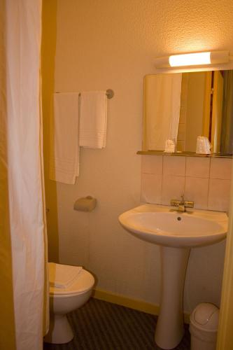 a bathroom with a sink and a toilet and a mirror at Hotel de L'Opéra in Bordeaux