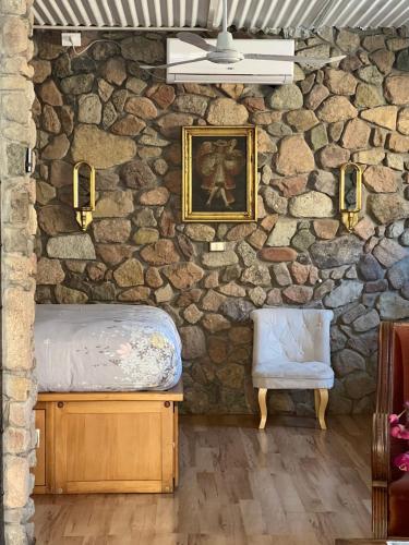 a room with a stone wall with a bed and a chair at Cabañas Caballieri in Pisco Elqui