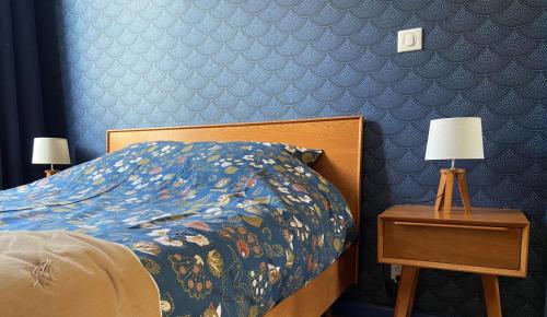 Una cama con un edredón colorido y una mesa con lámparas. en Le KEMPER - Cœur de ville, en Quimper