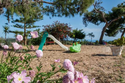 a playground with a greenroller in a park with flowers at Pine tree Apartment & sunset in Ágios Nikólaos