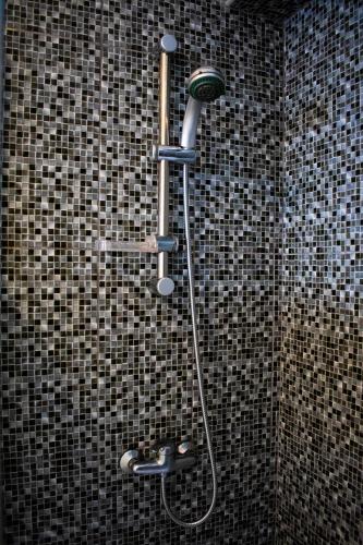 a shower in a bathroom with a tile wall at Domus Nostra in Furnas