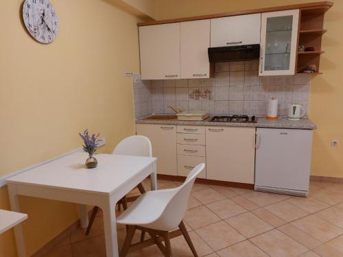 a kitchen with a white table and white chairs at Studio Apartman Viktoria Rabac in Rabac