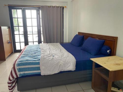 sypialnia z łóżkiem z niebieskimi poduszkami i oknem w obiekcie Lippo carita selatan condo 3bedroom langsung pantai w mieście Carita