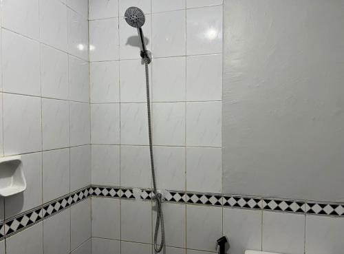 a shower in a white tiled bathroom at Villa Lippo carita langsung pantai 3bedroom in Pandegelang