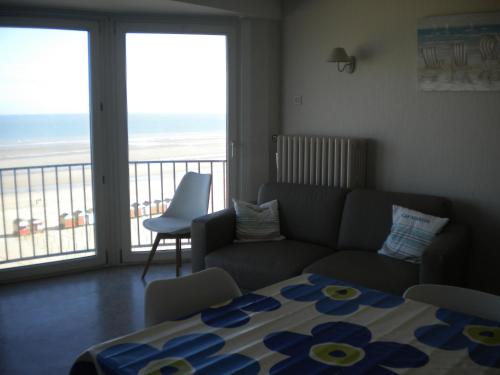 ein Wohnzimmer mit Couch und Blick aufs Meer in der Unterkunft Apartment Sandeman in De Panne