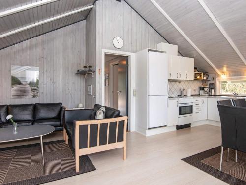 a living room with a couch and a table and a kitchen at 6 person holiday home in Bl vand in Blåvand