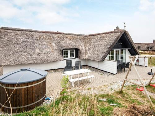 Cabaña con techo de paja y bañera de hidromasaje frente a ella en 8 person holiday home in Ringk bing, en Klegod