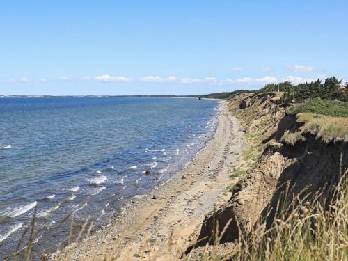 a beach with water and a rocky shoreline at 8 person holiday home in Farsø in Farsø