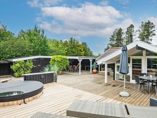 an outdoor deck with a table and an umbrella at 6 person holiday home in Brovst in Brovst