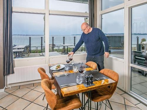 a man standing at a table with a glass of wine at 4 person holiday home on a holiday park in Faaborg in Fåborg