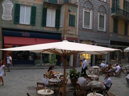 un grupo de personas sentadas en mesas bajo un paraguas en Appartamento dei Sassetti, en Savona