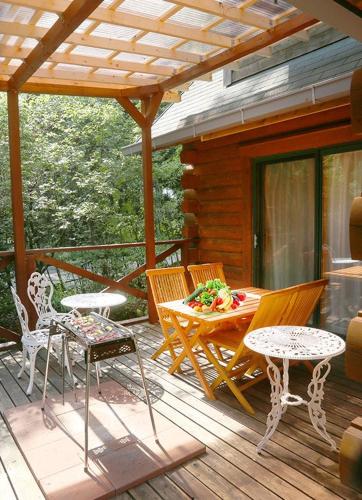 eine Veranda mit einem Tisch und Stühlen auf einer Terrasse in der Unterkunft コテージ　チャオ in Nasushiobara