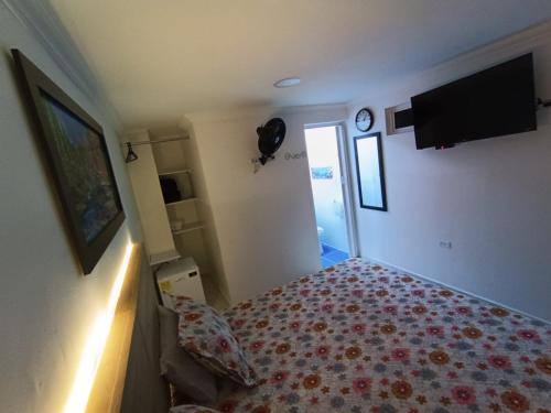a bedroom with a bed and a tv on the wall at Hotel Eterna Primavera in Medellín
