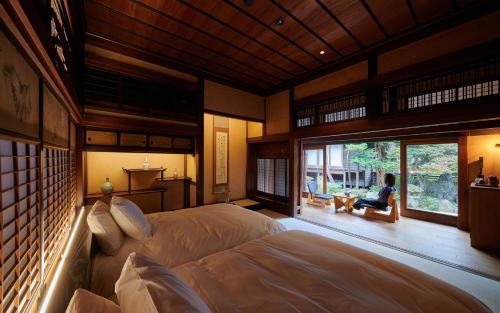 sypialnia z łóżkiem i osoba siedząca na krześle w obiekcie BYAKU Narai w mieście Shiojiri