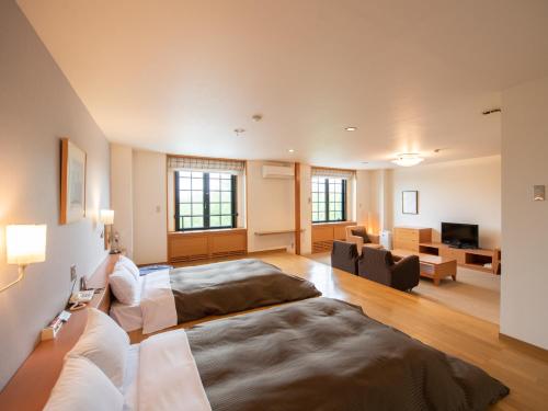 立科町にあるTabistホテル コロシアム・イン・蓼科のベッドルーム1室(ベッド2台付)、リビングルームが備わります。