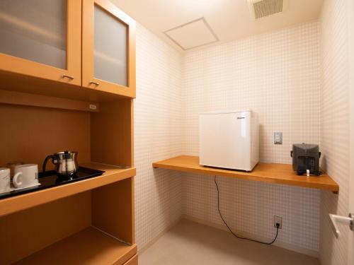 a small kitchen with a white appliance on a shelf at Tabist Hotel Colosseum Inn Tateshina in Tateshina