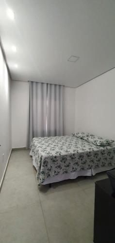 a bedroom with a bed with a flowered blanket at Casa branca in Bananeiras