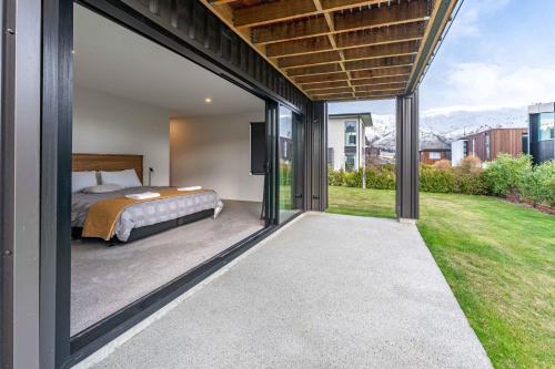 a bedroom with a bed and sliding glass doors at La Cachette Wanaka in Wanaka
