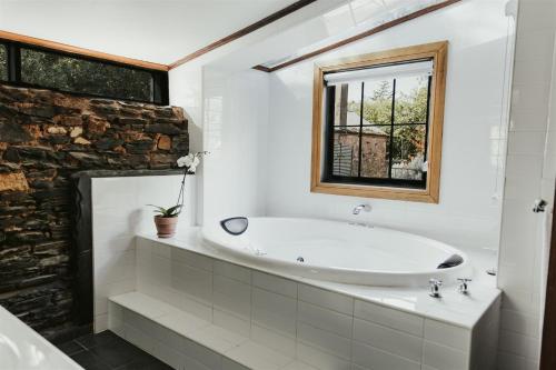 baño blanco con bañera y ventana en Mintaro Cottage, en Mintaro
