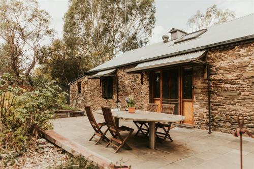 a patio with a table and chairs in front of a stone building at Mintaro Cottage in Mintaro